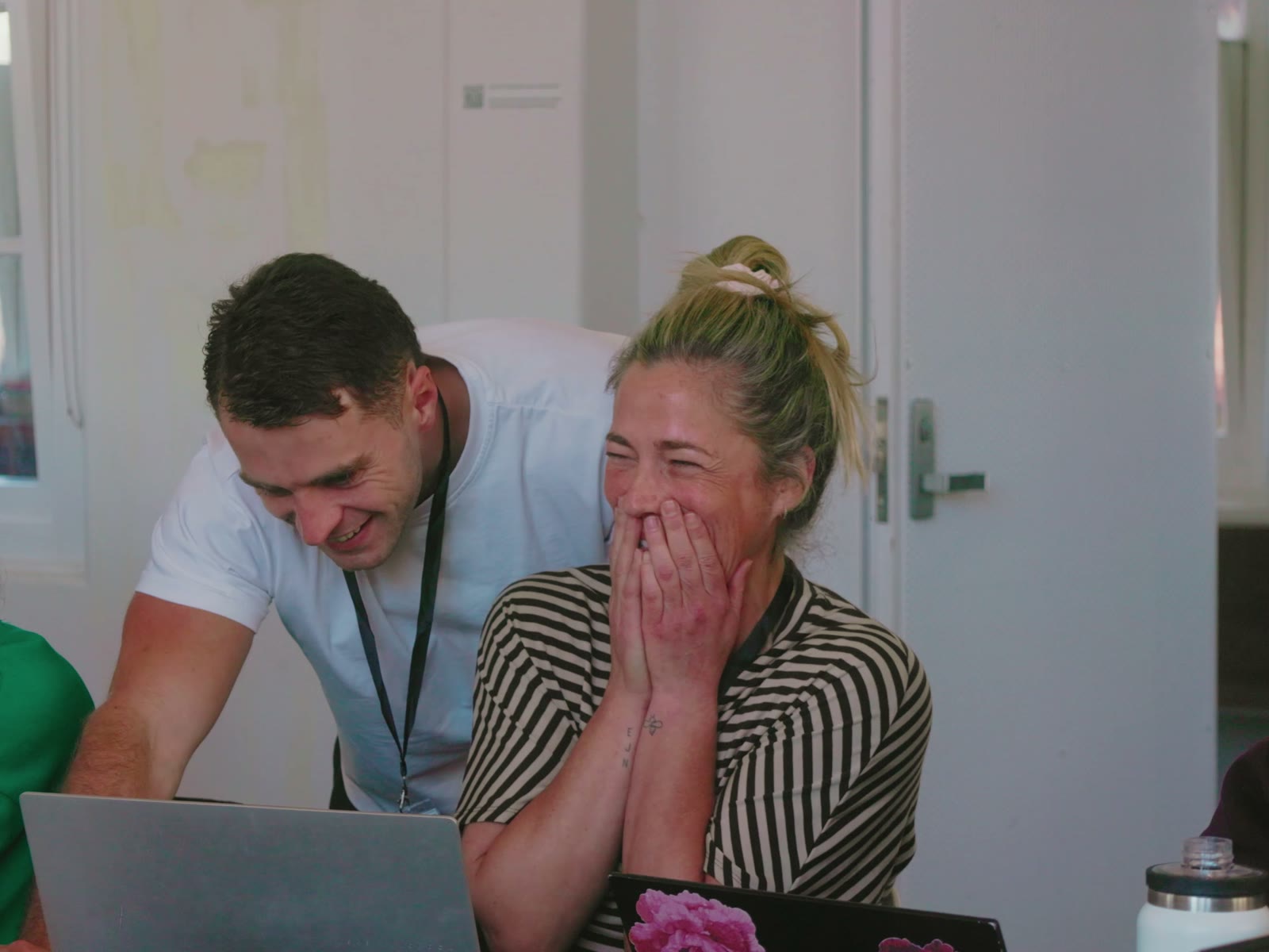 Two attendees laughing at a laptop mid-build